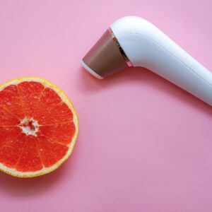 Contactless Clitoral Stimulator Satisfyer and ripe grapefruit on a pink background